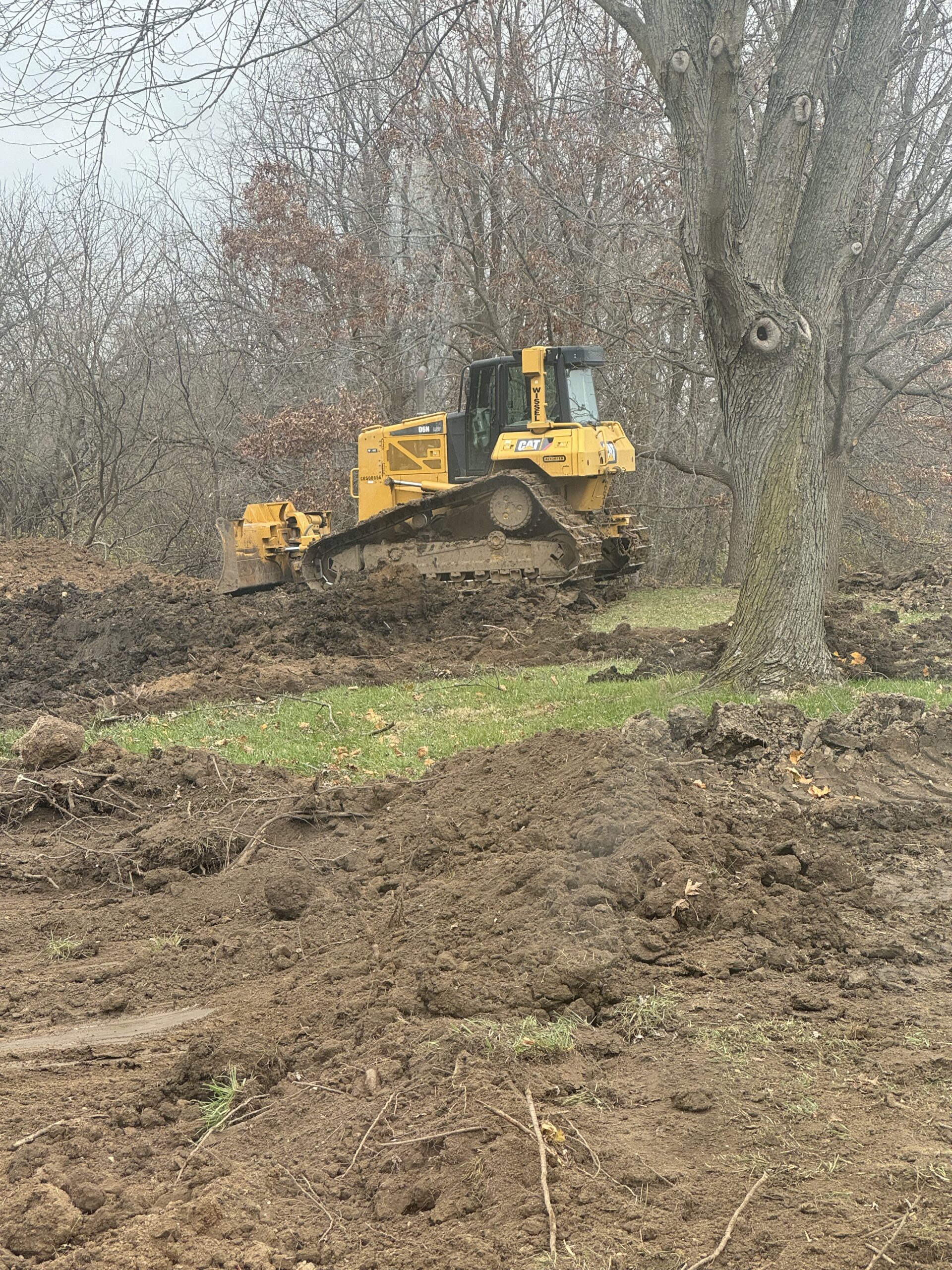 Yellow Bulldozer Operating in a Grassy Area Yellow bulldozer working on a construction site with disturbed soil and vegetation.