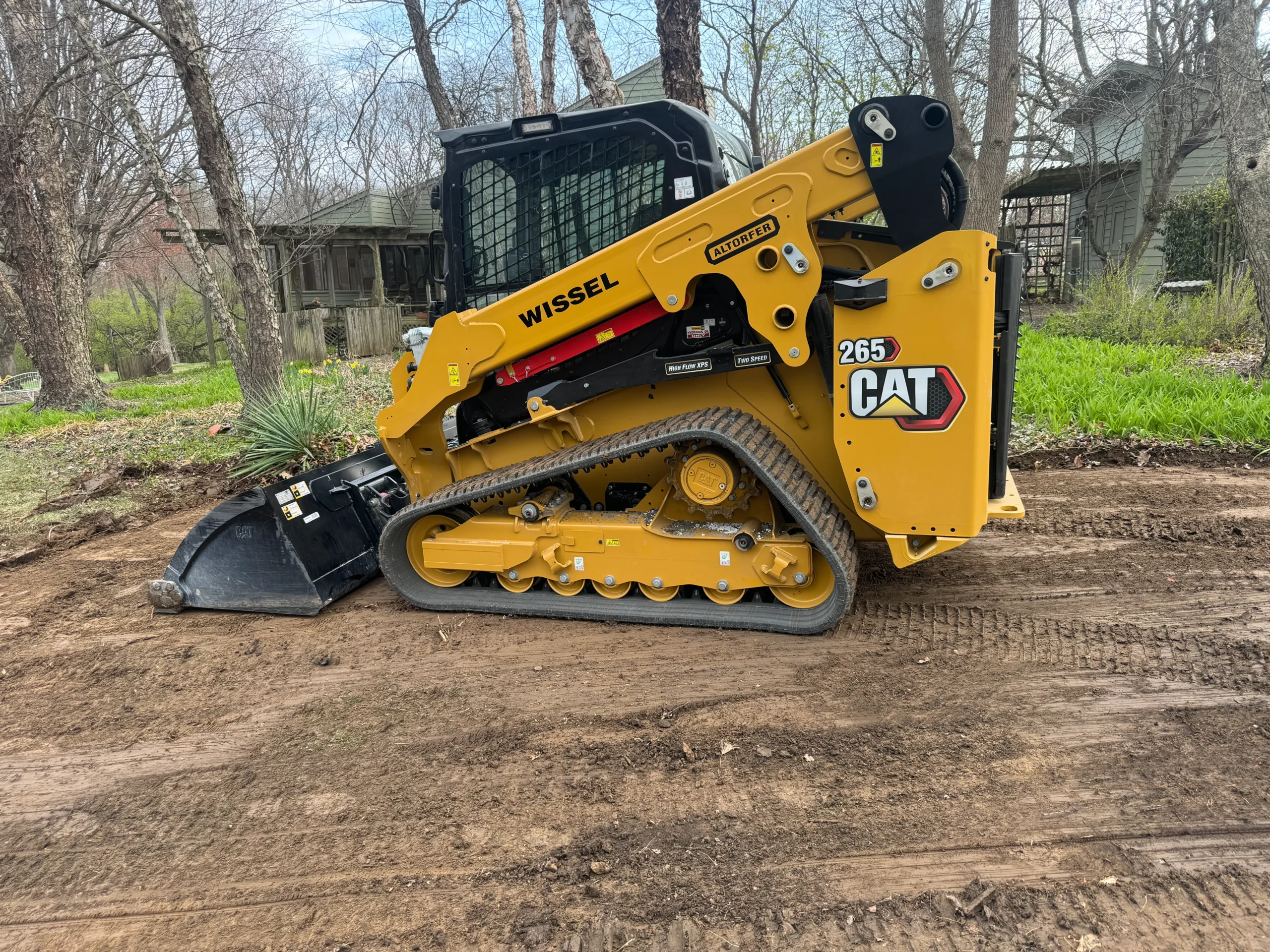 Caterpillar 265 skid steer loader with tracks and front bucket on a dirt surface.